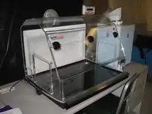 A clear plastic box on a desk with clear tubes emerging from its top