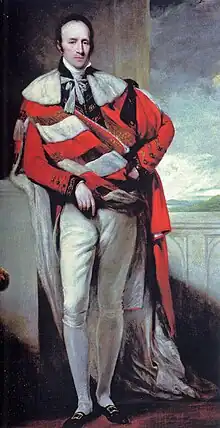 A man standing, wearing a red and white cloak, and white trousers and stockings