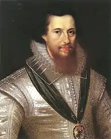 A portrait of Robert Devereux, who is portrayed wearing a silver shirt. He has shoulder-length black hair and a brown beard which reaches down to his collar. Devereux is wearing a medal suspended from a green ribbon.