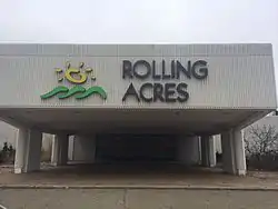 Abandoned entryway to a shopping mall. Present is a sign reading "Rolling Acres"