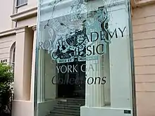 a classical building with a modern sign identifying it as the Royal Academy of Music