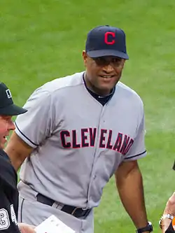 A man in a gray baseball uniform and navy cap