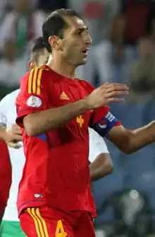 A man wearing a red football jersey with yellow trim.