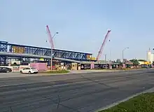 Photo of a gated off construction site with cranes and other equipment visible