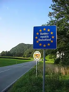 Two road-signs on the side of an open stretch of a two-lane highway.