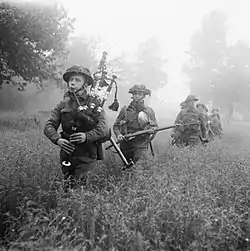 Bagpiper leading a line of soldiers though thigh-high growth