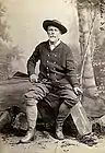 Studio portrait with his Gibbs Metford rifle and hunting attire.