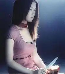 A woman stares off to her left, while cutting an apple in her hands.