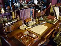 Cluttered desk with books, jars, sculpted elephants and other objects