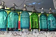 A row of colorful soda siphons on a shelf