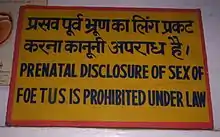 Sign in an Indian clinic reading "Prenatal disclosure of sex of foetues is prohibited under law" in English and Hindi.