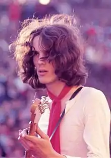 Young, long-haired man playing guitar onstage