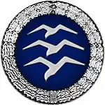 Badge: on a blue disc, silhouette of three white birds stacked in flight, the whole surrounded by a silver wreath