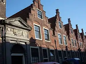 The gable stone before restoration with a view of the houses on the right