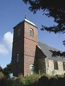 A stone church with a prominent brick tower, capped with a cupola