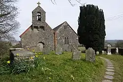 double-gable church with belfry, and graveyard in foreground