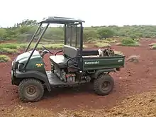  Small two-seater vehicle with a canopy for the passengers and an open load bed for cargo.