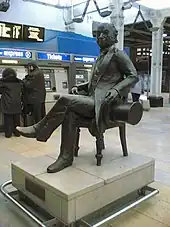 A black statue of a seated man holding a top hat