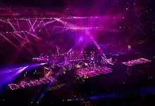 A faraway image of a stage with purple lights flashing from all around on it.