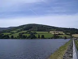 A dam with a water tower, and a hill immediately behind