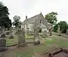 A severe, grey single-storey chapel with Georgian windows and small bellcote. The churchyard has lines of headstones in neat rows.