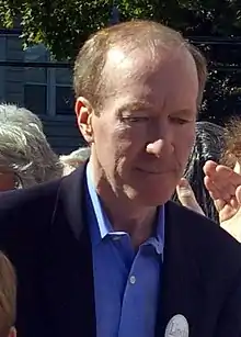 Tom Scott in blue shirt and dark jacket, looking down