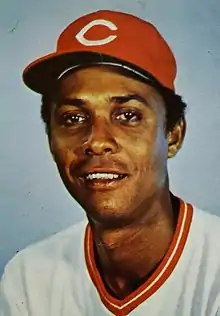 A man in a white baseball jersey and red cap