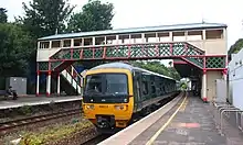 A green GWR train under the footbridge at Torre