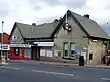 A beige-bricked building with a rectangular, dark blue sign reading "TOTTERIDGE & WHETSTONE STATION" in white letters all under a blue sky