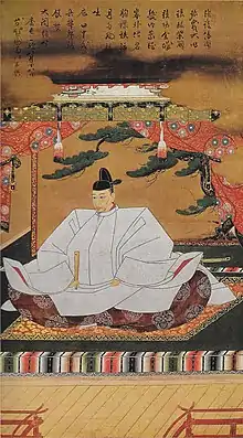 In this artwork a Japanese man in with a black hat and traditional clothing sits on the floor with a closed fan in his right hand