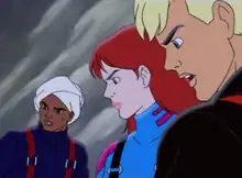 Characters Hadji Singh, Jessie Bannon, and Jonny Quest are shown with faces emphasized in an ice setting. Hadji is very tan-skinned, wearing a turban, navy blue sweater, and red suspenders. Jessie is pale-skinned with red hair and green eyes, and is wearing a blue snow-suit with pink highlights and black suspenders. Jonny has blonde hair and blue eyes, and is lightly tanned; he's wearing a black snow-suit with red suspenders.