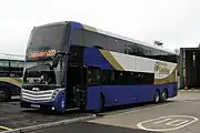 A white, blue and gold coach parked in a bus station.