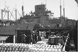 USS LST-483 and USS President Monroe (AP-104) docked at Adak, Alaska, 20 September 1943. As SeaBees load a barge with material for the airfield they are building at Tanaga Island.