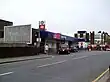 A brown-bricked building with a rectangular, dark blue sign reading "Upminster" in white letters and a pink sign reading "c2c"