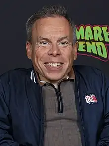 A man smiling in front of a poster