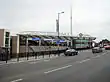 A terracotta-coloured building with a rectangular, light blue sign reading "WEMBLEY PARK STATION" in white letters all under a cloudy sky