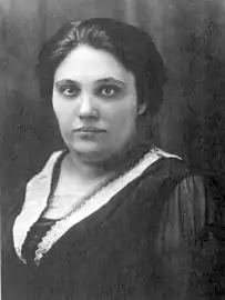 a young woman with dark hair and eyes, wearing dark dress with a lace collar. She is not smiling.